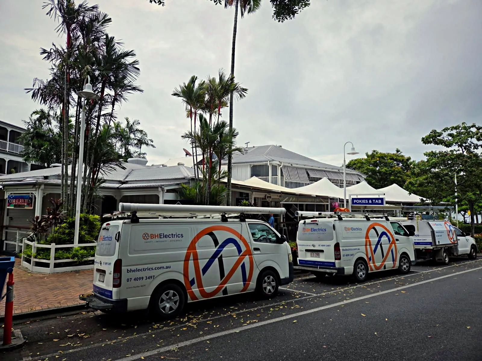 BH Electrics vans parked outside the Court House Hotel, Port Douglas, under the POKIES & TAB sign
