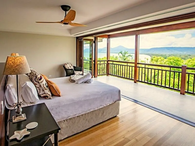 A bedroom with a ceiling fan overlooking the garden