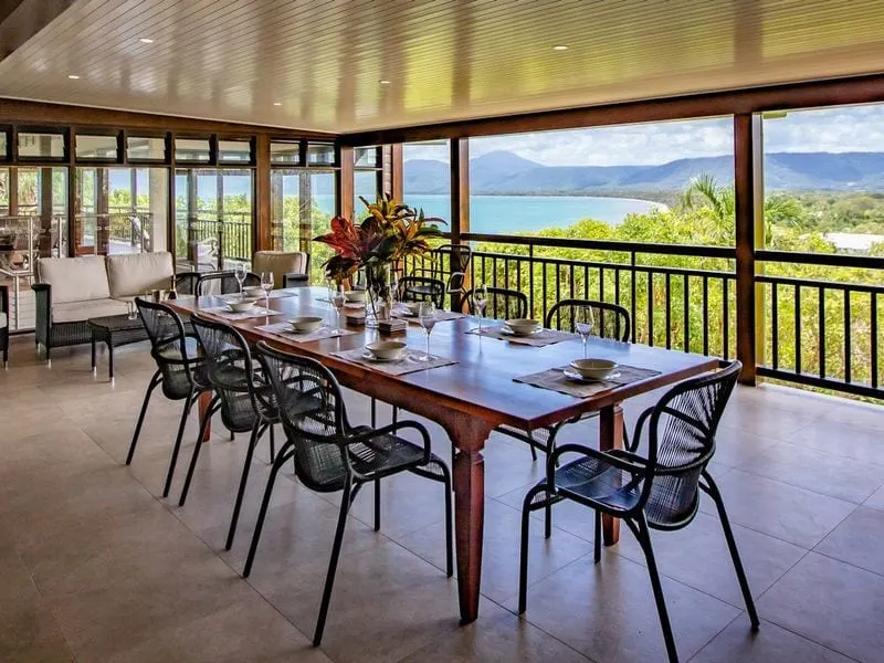 The covered dining deck at Bangalow, downlights in the ceiling, looking out over Four Mile Beach to the ranges