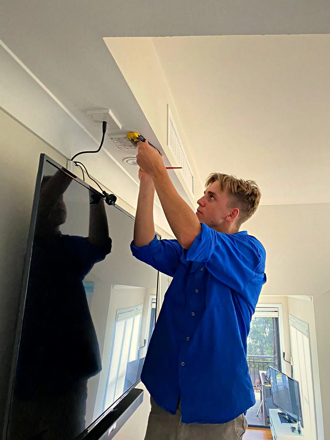 A BH Electrics electrician wiring a wall-mounted television
