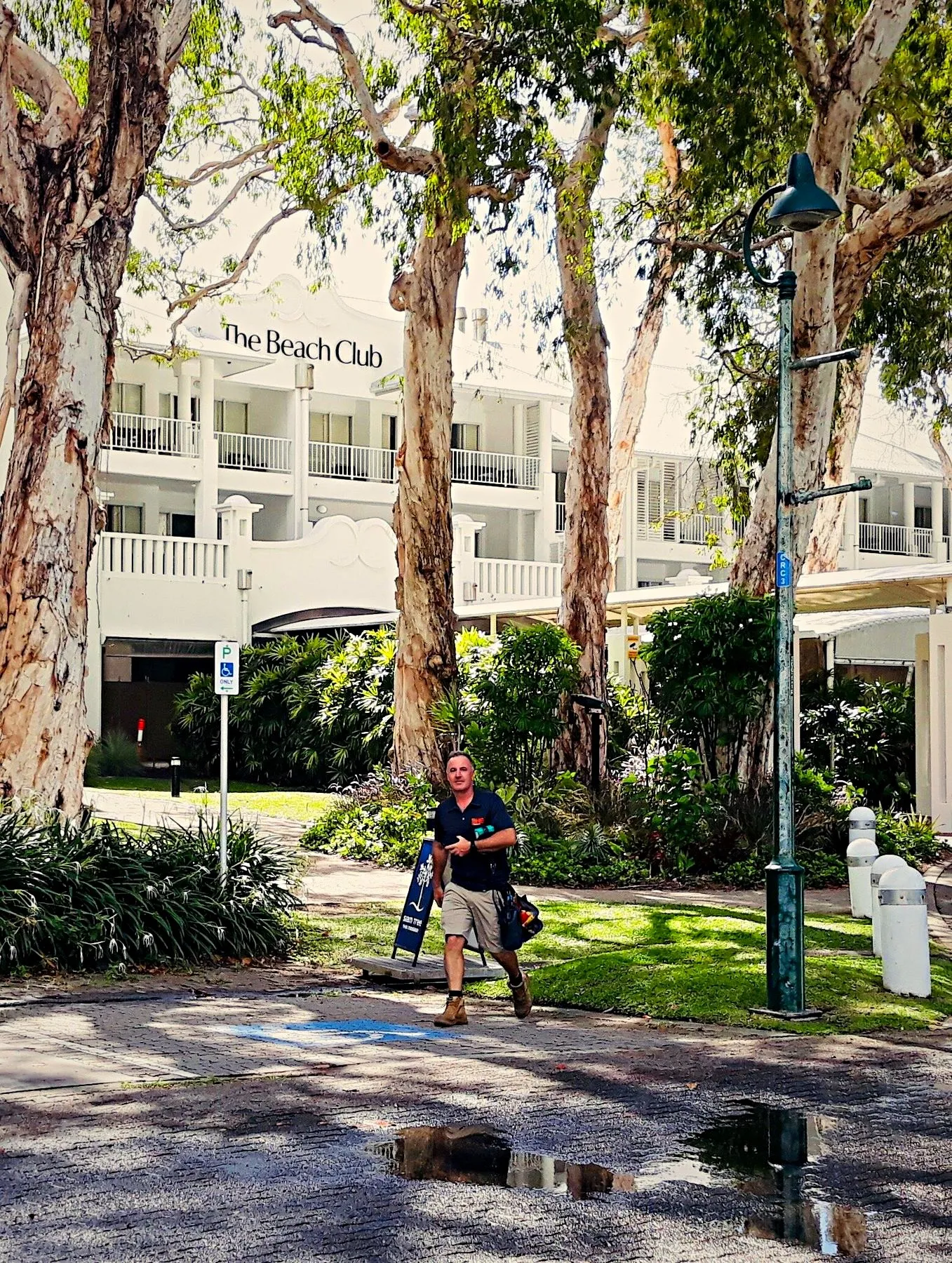 A BH Electrics electrician walking in to a job at The Beach Club, Palm Cove, through the paperbarks on the esplanade