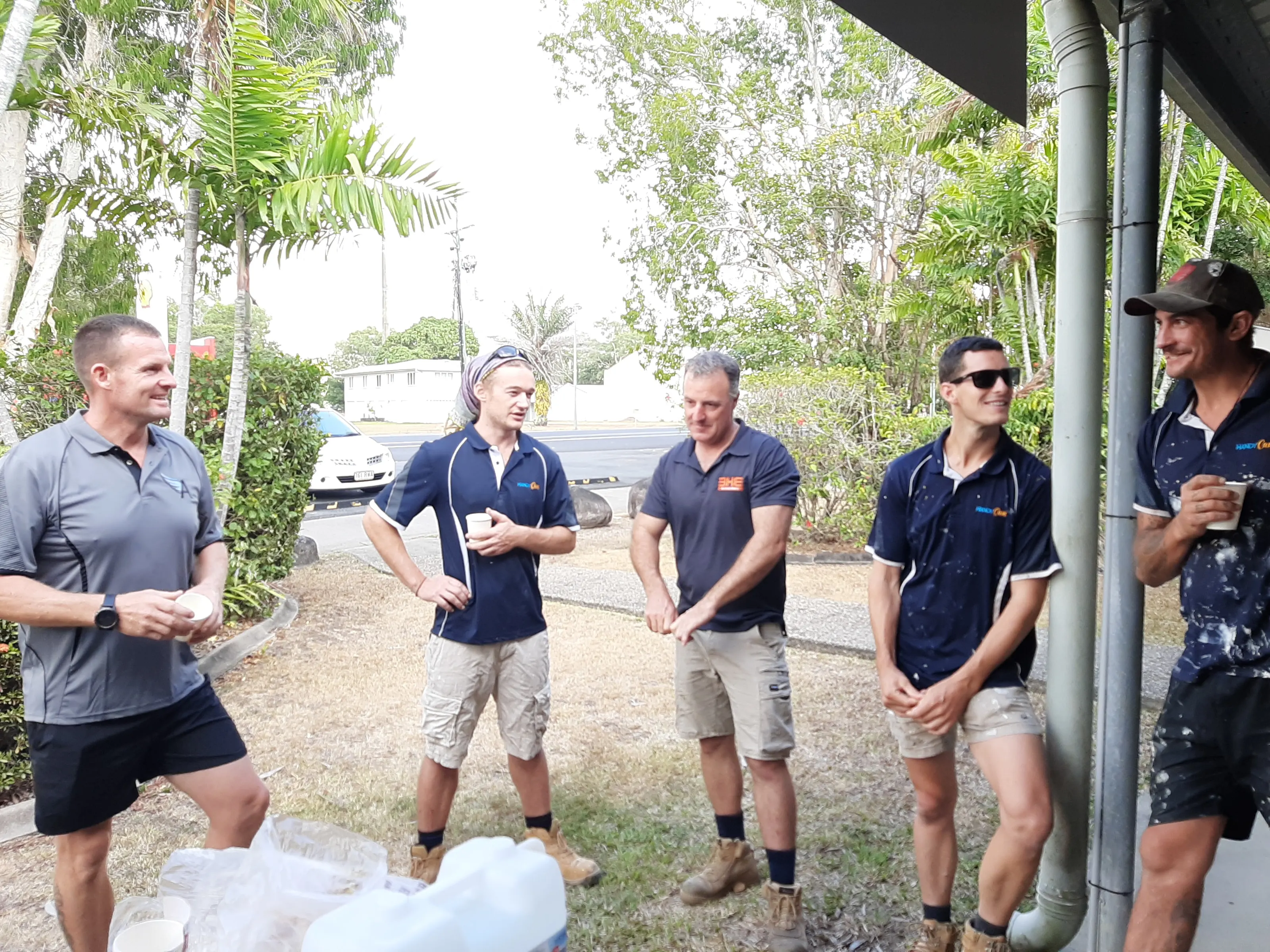 The BH Electrics crew standing with the builder on a nature strip at smoko, halfway through a job