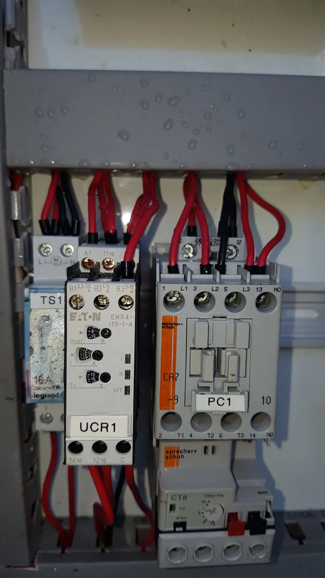 A contactor, motor overload and phase-failure relay on the rail inside a control panel