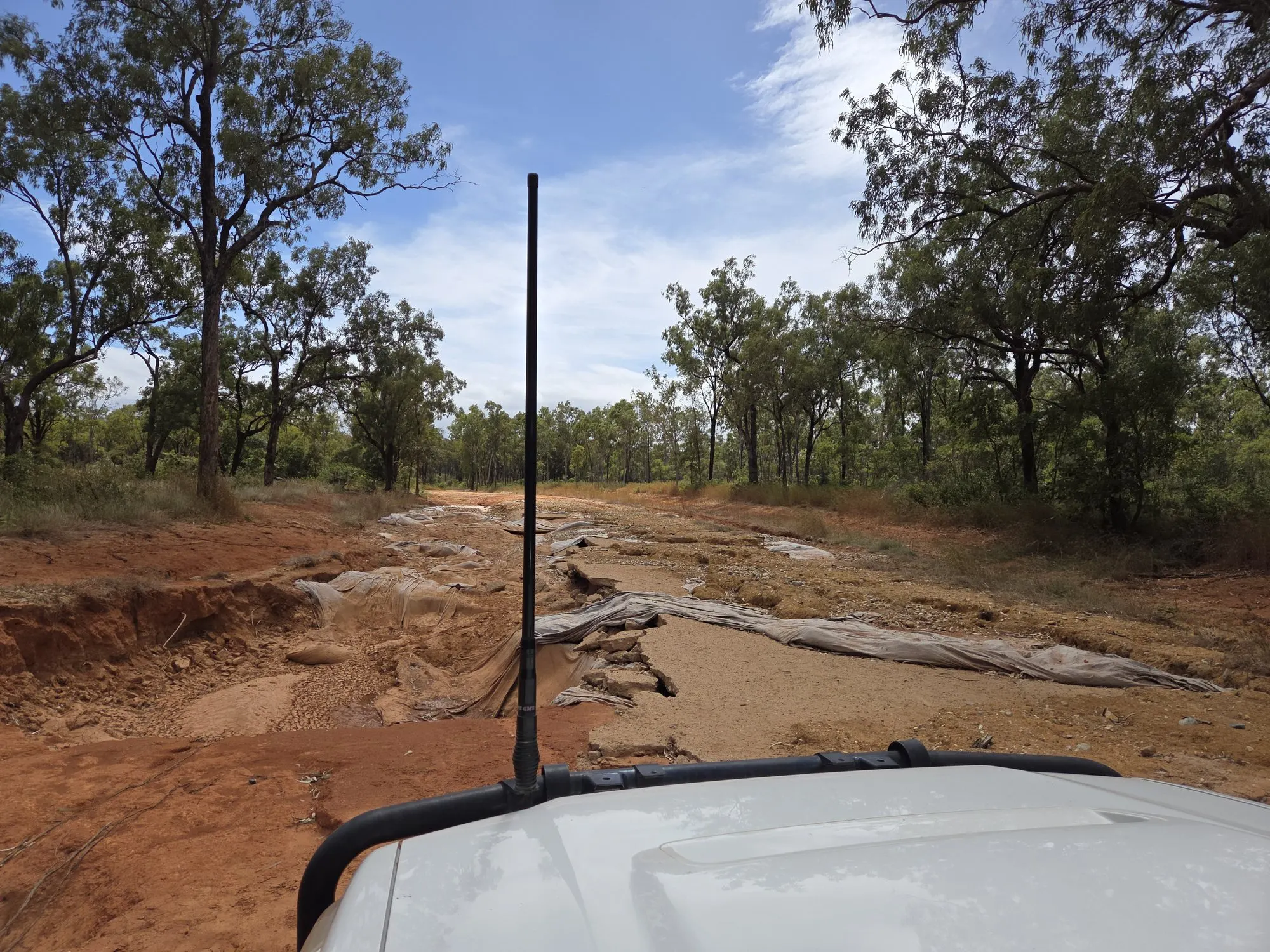A washed out red dirt road on the way to a remote ranger base, seen over the bonnet of the BH Electrics four wheel drive