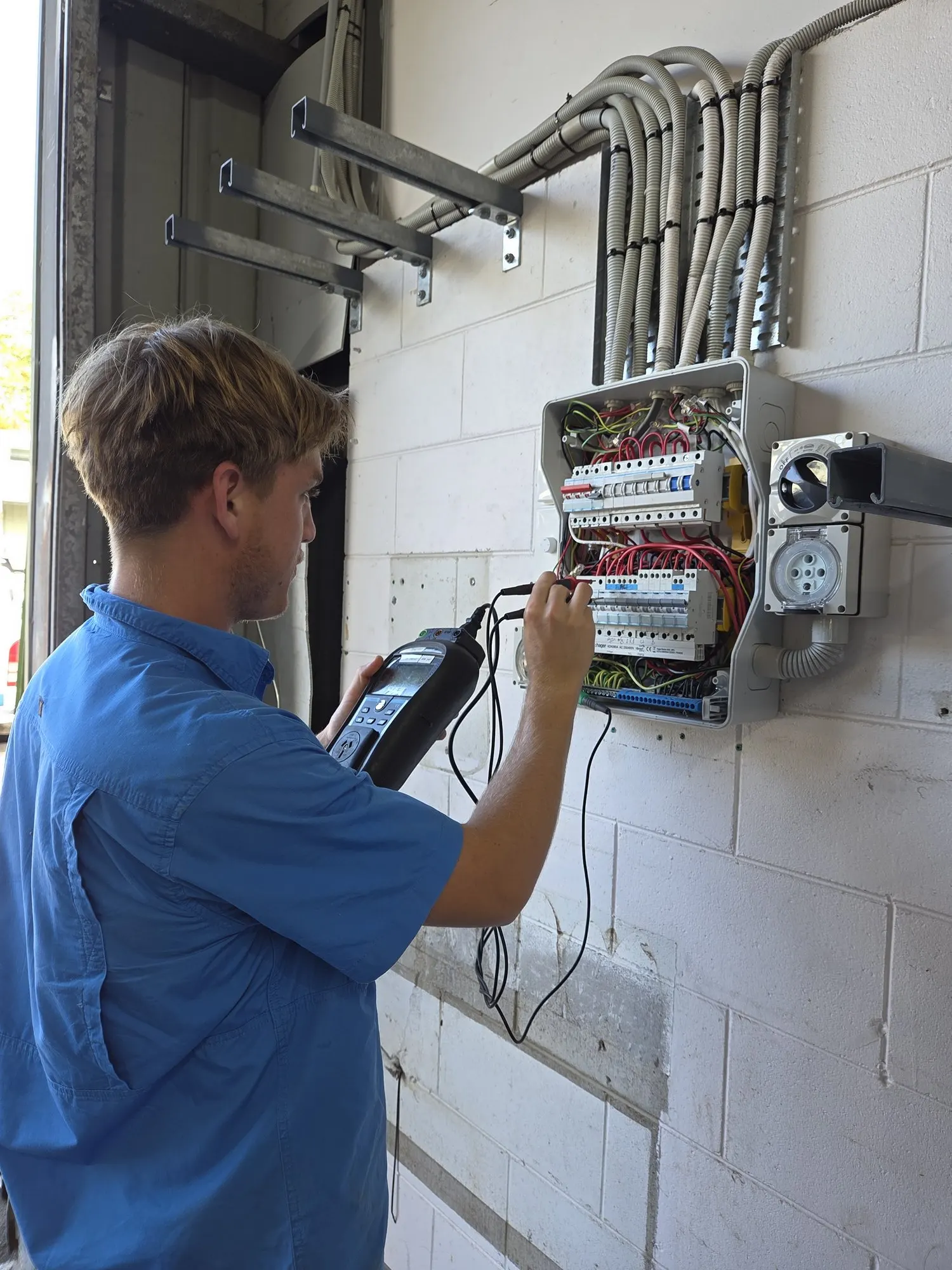 Close work at an open switchboard, test probe on an RCD, tester in hand