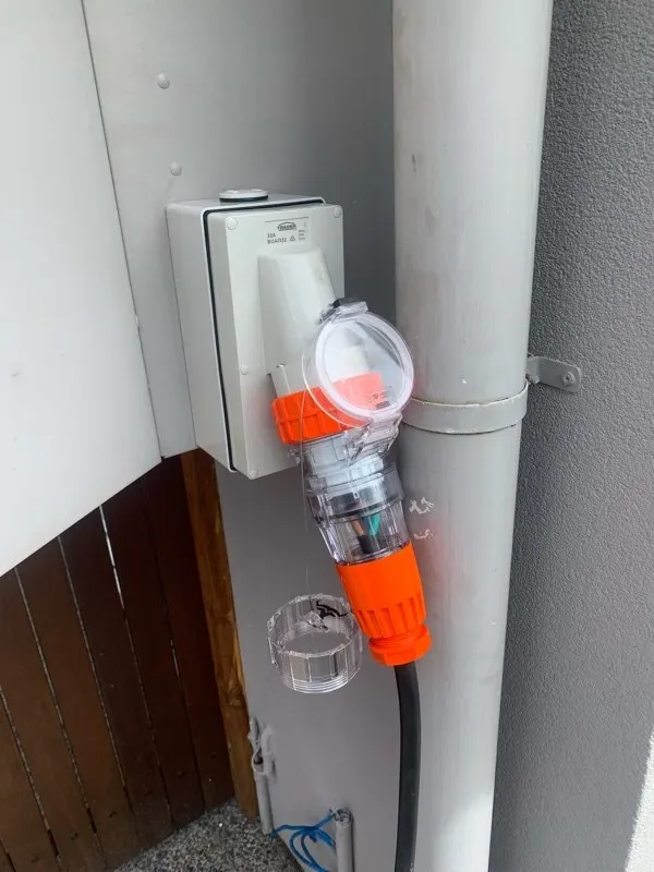 A weatherproof generator inlet on an external wall with the changeover lead plugged in