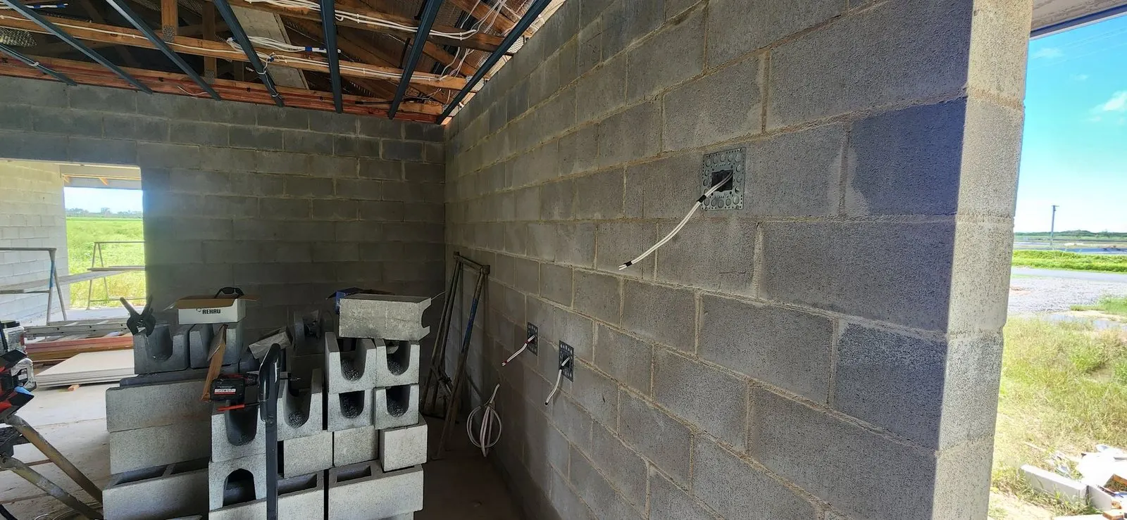 Cable tails and mounting brackets set into a blockwork wall during rough-in on a new house