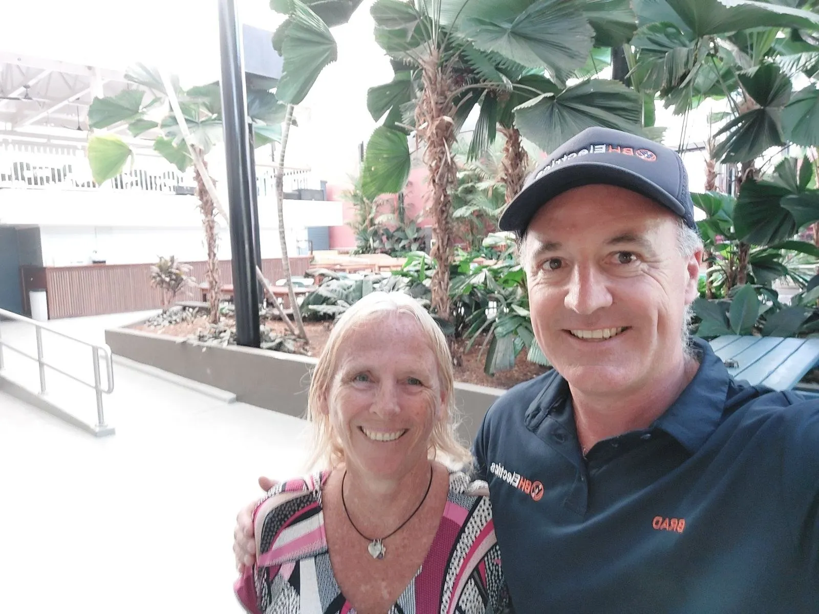 Brad Sims and a Port Douglas customer smiling together outside her home after a job