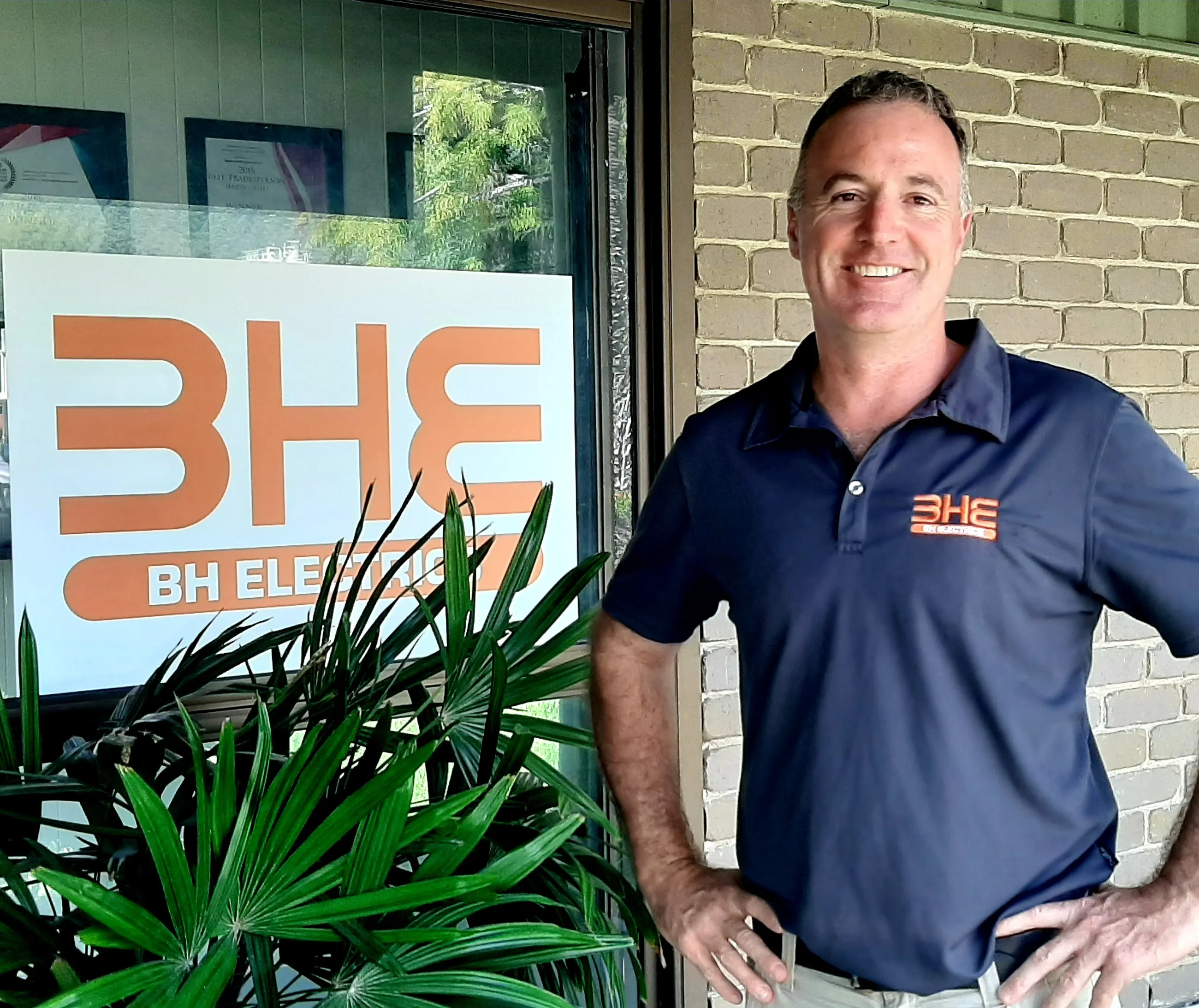Brad Sims outside the BH Electrics workshop at Craiglie, beside the orange BHE sign