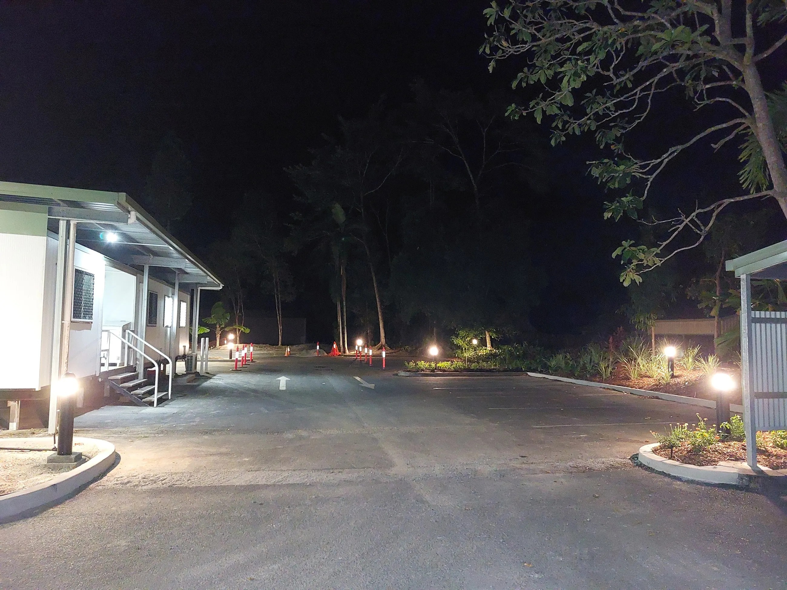 A driveway and garden lit after dark, light spilling evenly across both verges