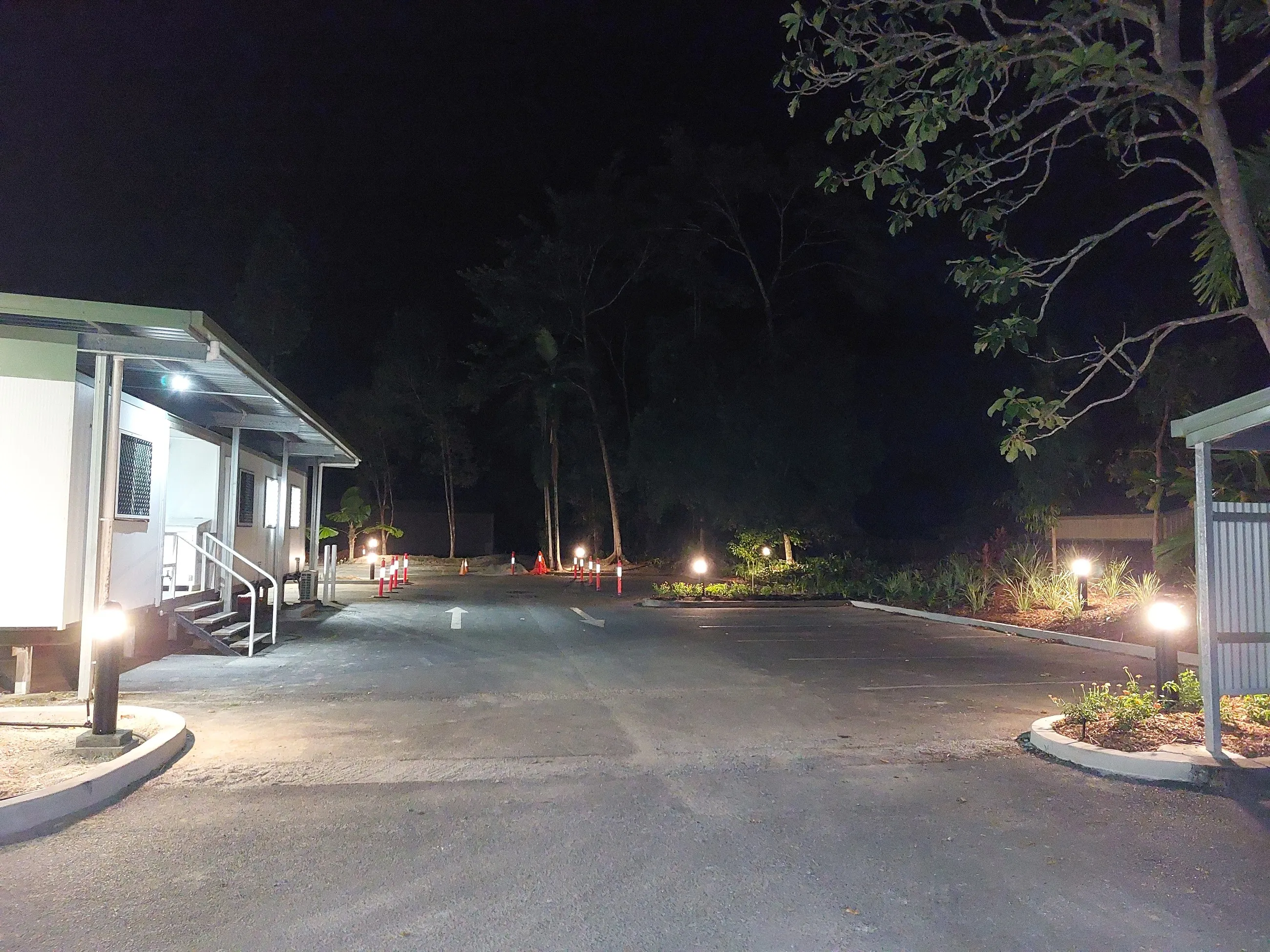 A driveway and garden lit after dark, light spilling evenly across both verges