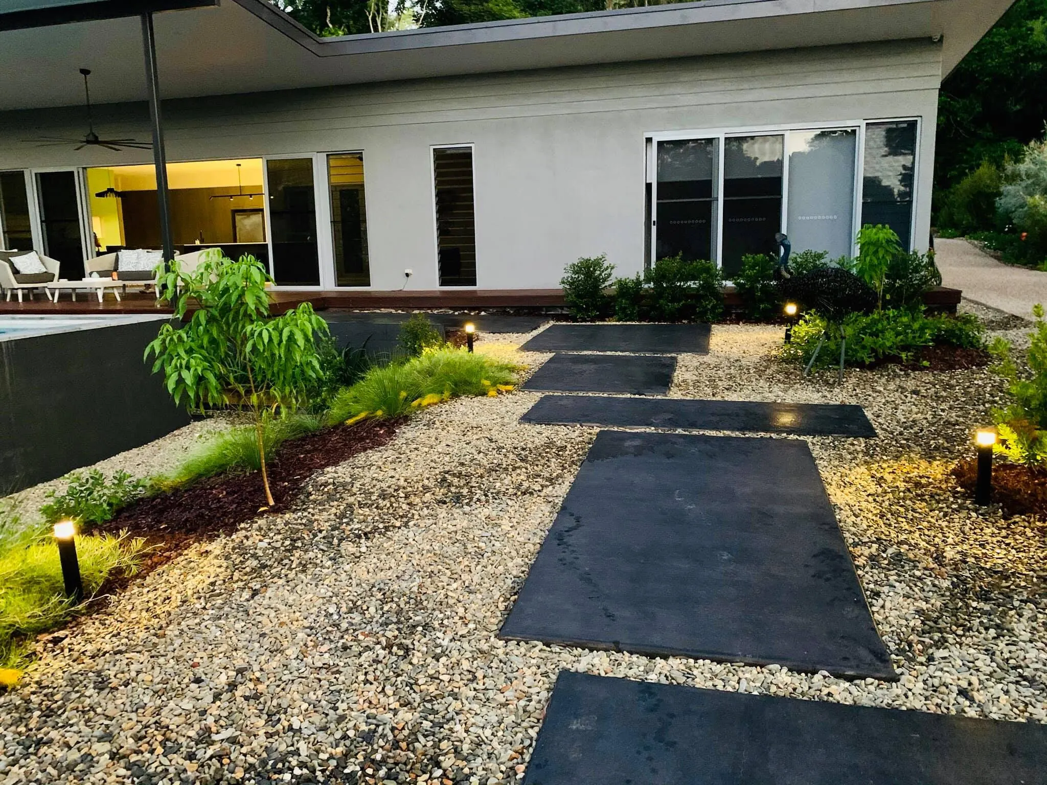 Garden lighting at dusk: low bollard path lights along slate stepping stones and a gravel garden beside a Far North Queensland home