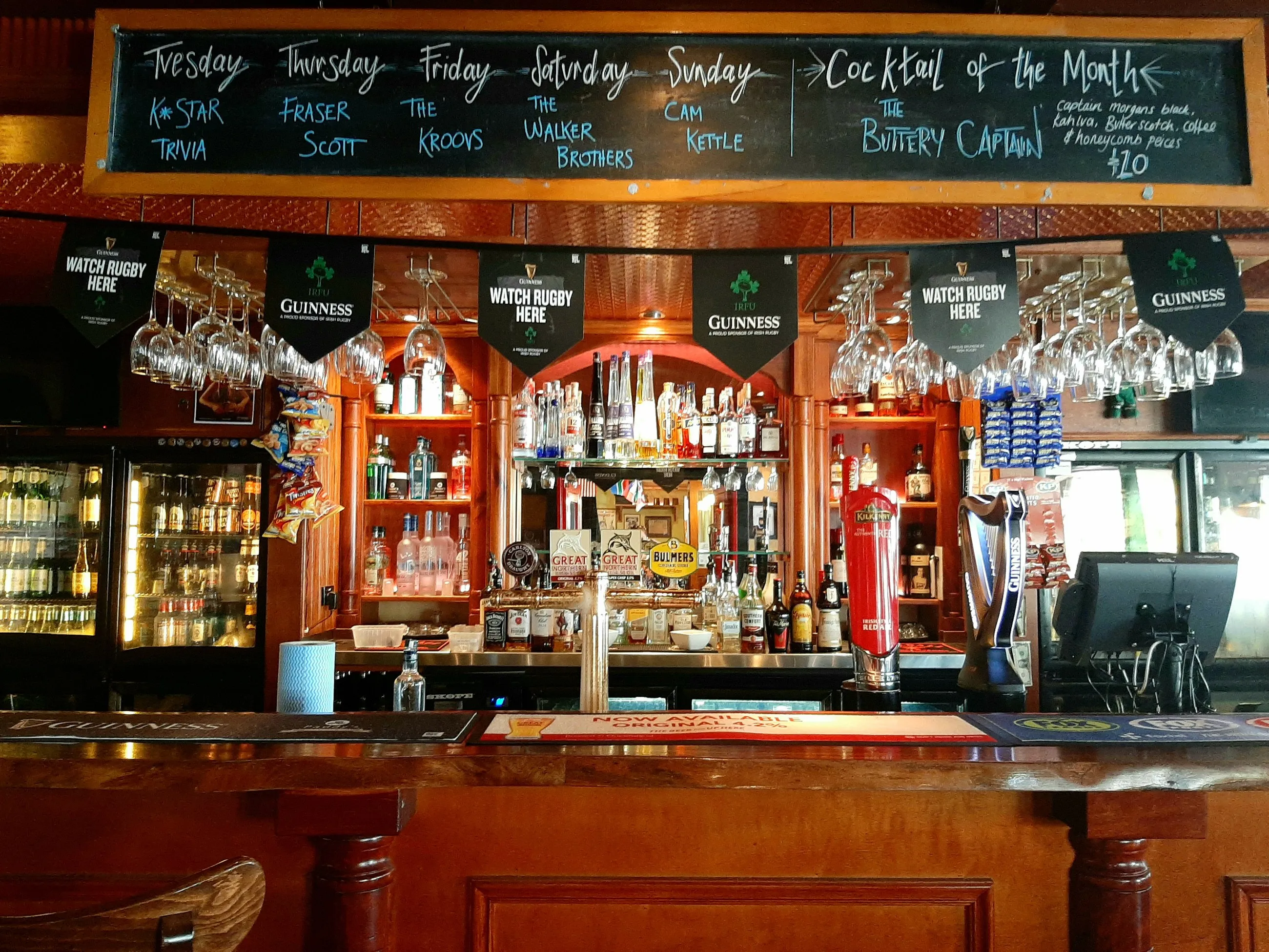 A lit back bar at night, spirits and glassware picked out under the shelf lighting