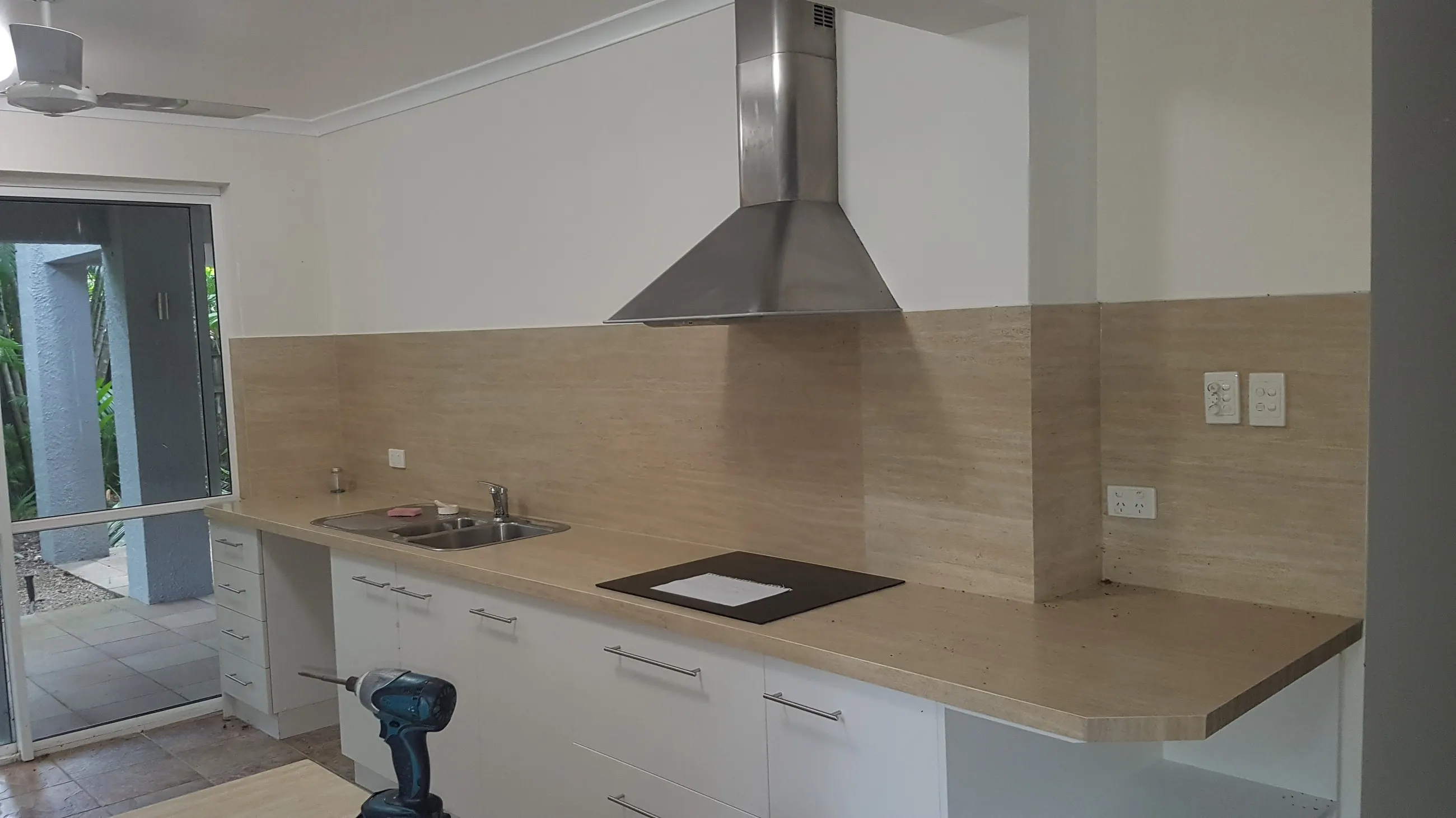 A finished kitchen with the rangehood, cooktop and bench lighting all wired in
