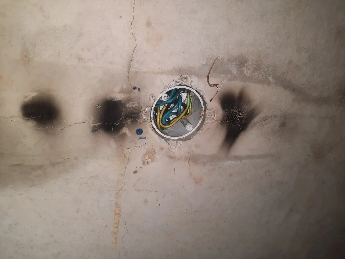 A ceiling rose scorched black on both sides, the cable burnt back to bare conductor