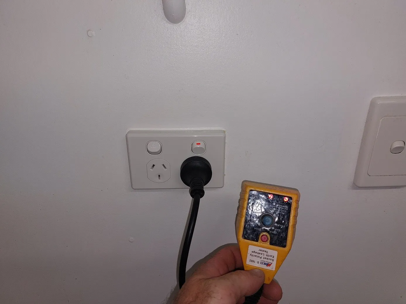 A socket tester plugged into a newly installed double power point, reading correct