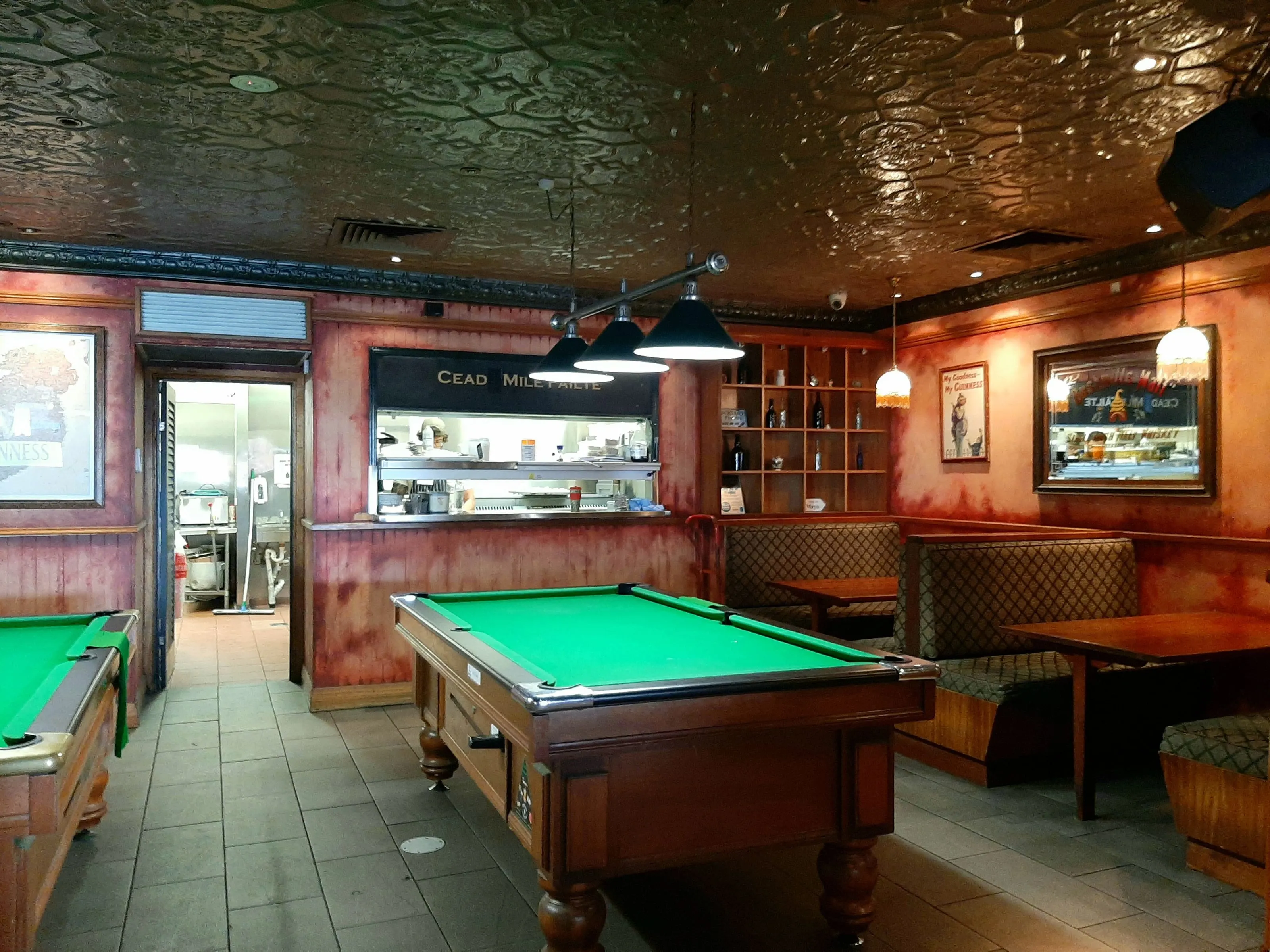 The pool room at Paddy's Irish Pub, a three-shade light bar over the table and pendants against the pressed metal ceiling