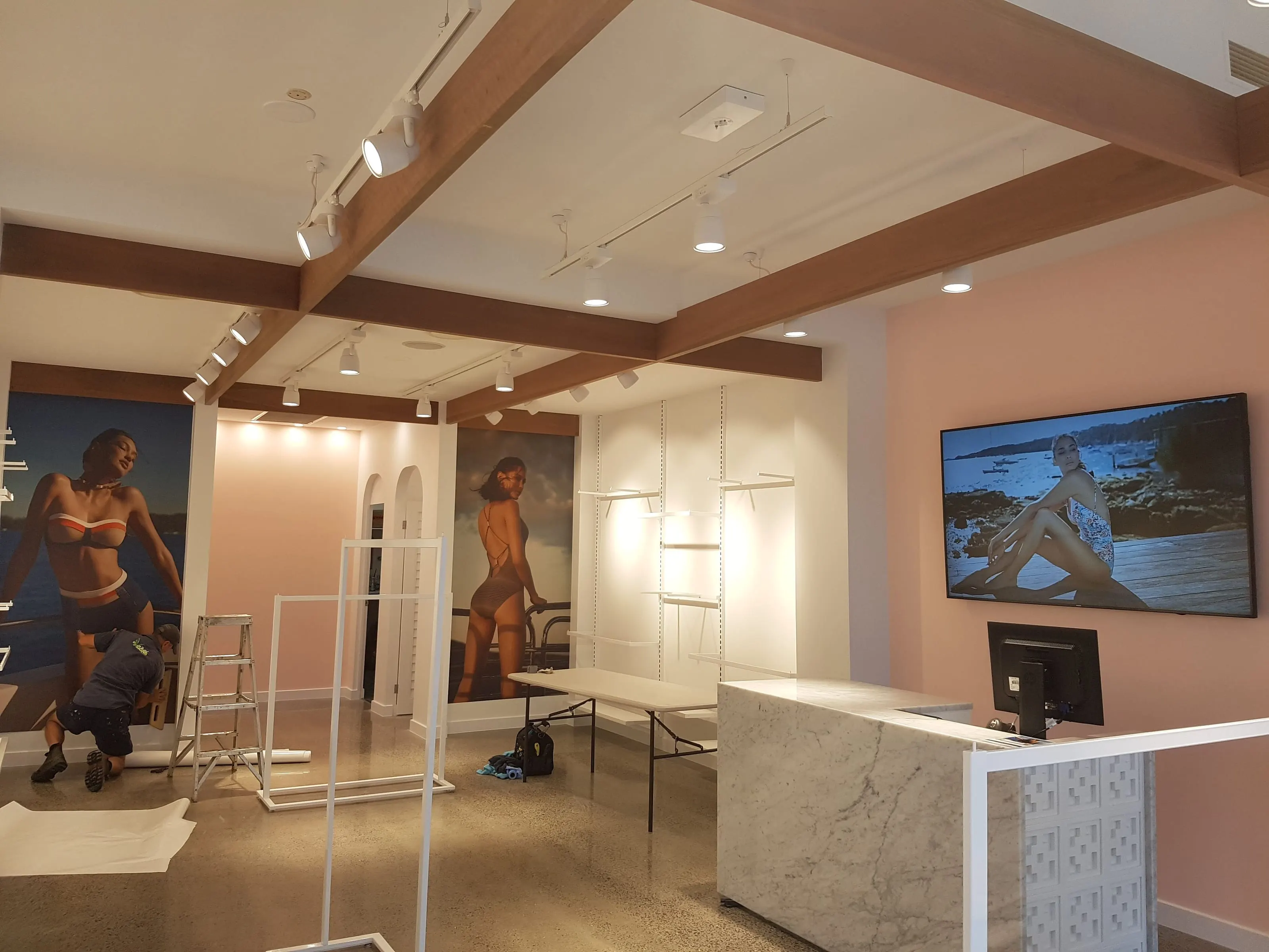 The Jets Swimwear store in Port Douglas near completion, track lighting run along the timber beams and a wall-mounted screen behind the counter