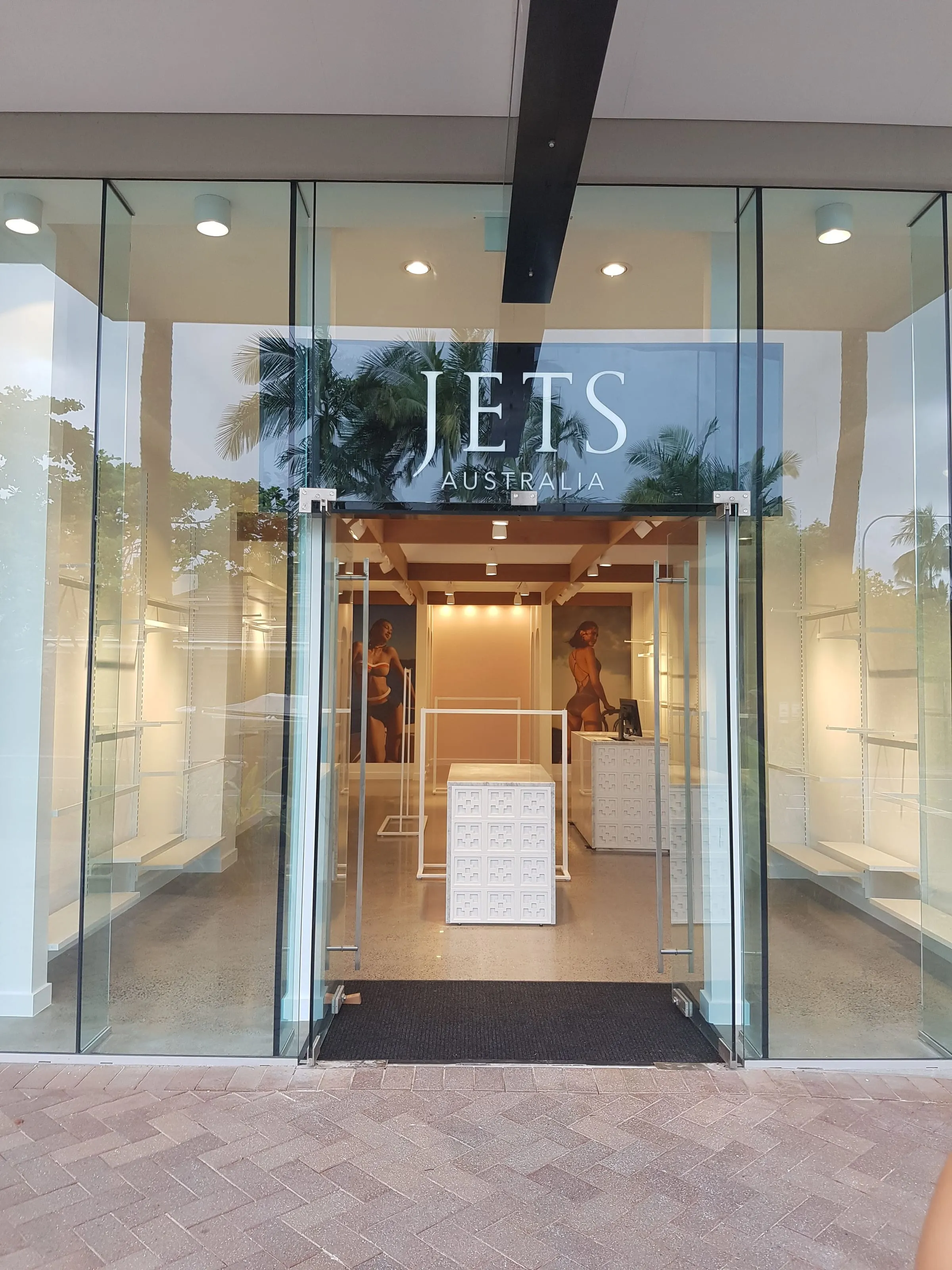 The Jets Swimwear shopfront, Port Douglas, the JETS Australia sign over open glass doors and the store lit inside