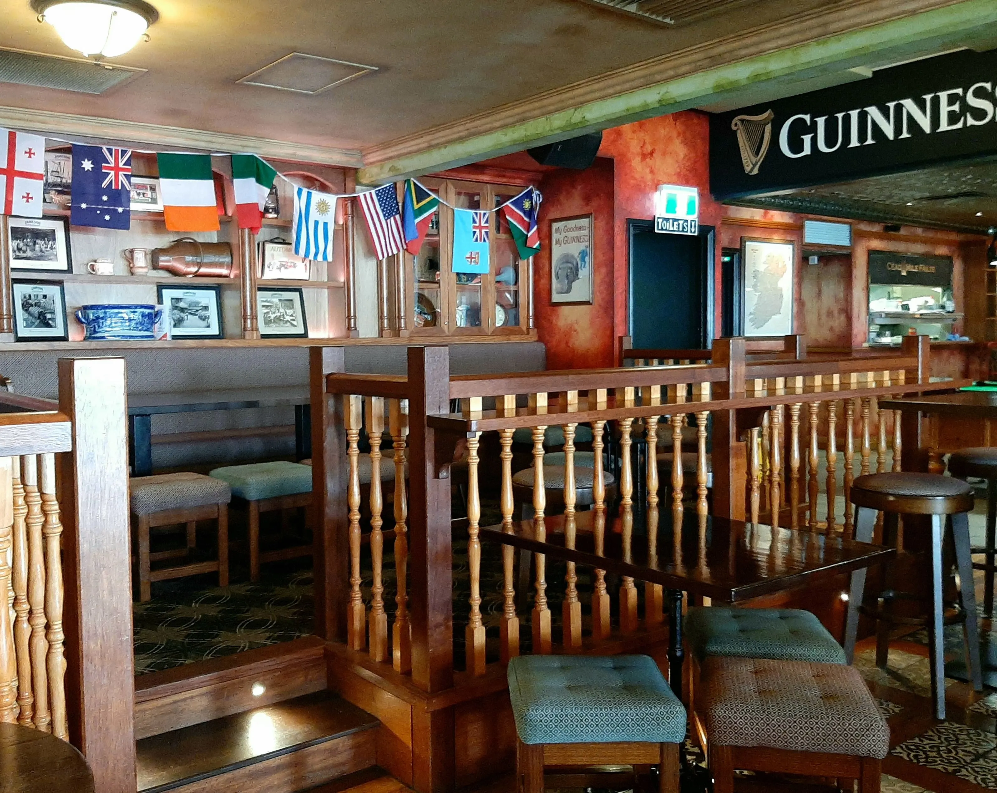 Timber booths and turned balustrades at Paddy's Irish Pub, flag bunting over the shelving and the Guinness fascia over the bar