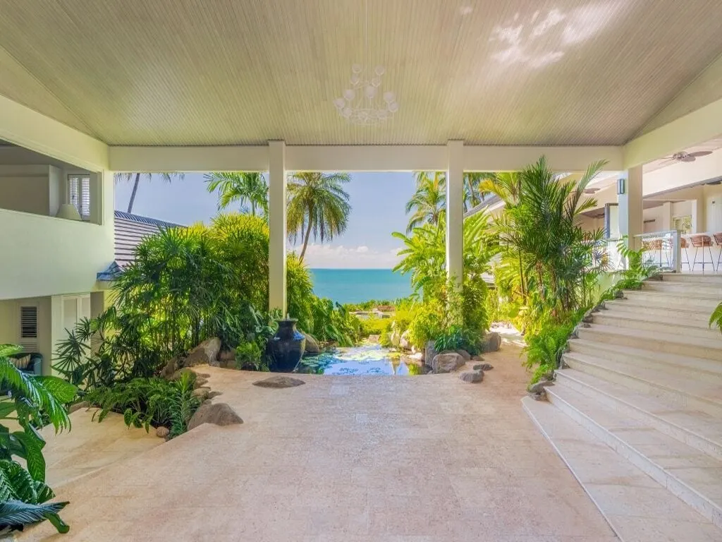 The covered entry at Cliffside, a pendant hung in the lined ceiling, looking through the garden and a lily pond to the Coral Sea