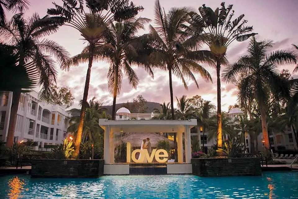 Peppers Beach Club & Spa, Palm Cove, at dusk: the lagoon pool, palms and the LOVE sign lit in the pavilion