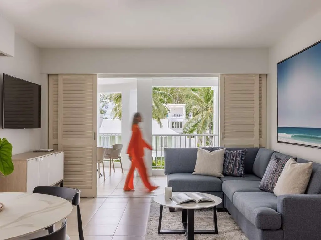 A refurbished suite at Peppers Beach Club & Spa, Palm Cove: a wall-mounted television, lounge and shutters open to the balcony