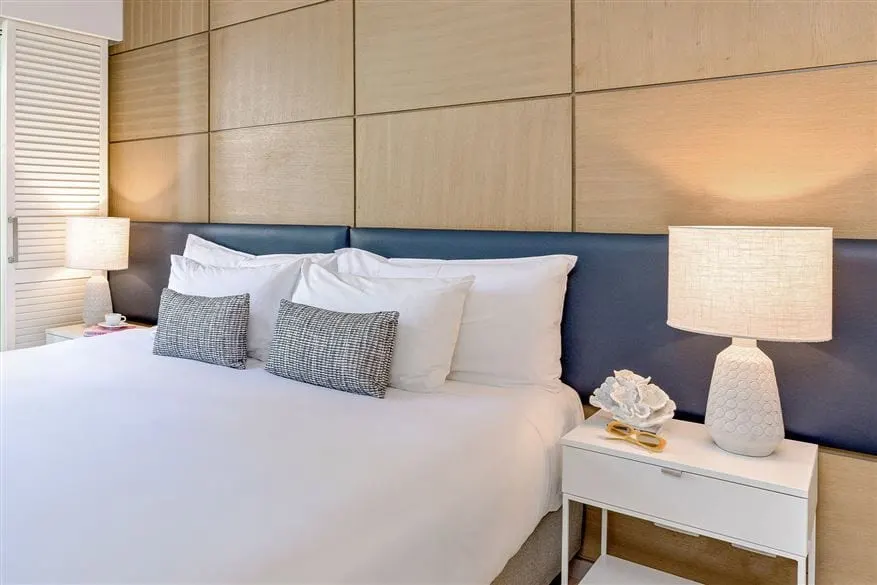 A refurbished bedroom at Peppers Beach Club, Port Douglas, lamps either side of a padded bedhead