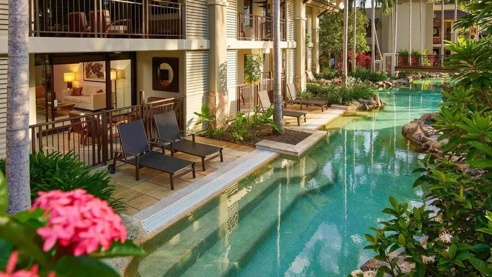 Swim-out apartments at Pullman Sea Temple, Port Douglas, lamps lit inside and the lagoon pool running along the terraces
