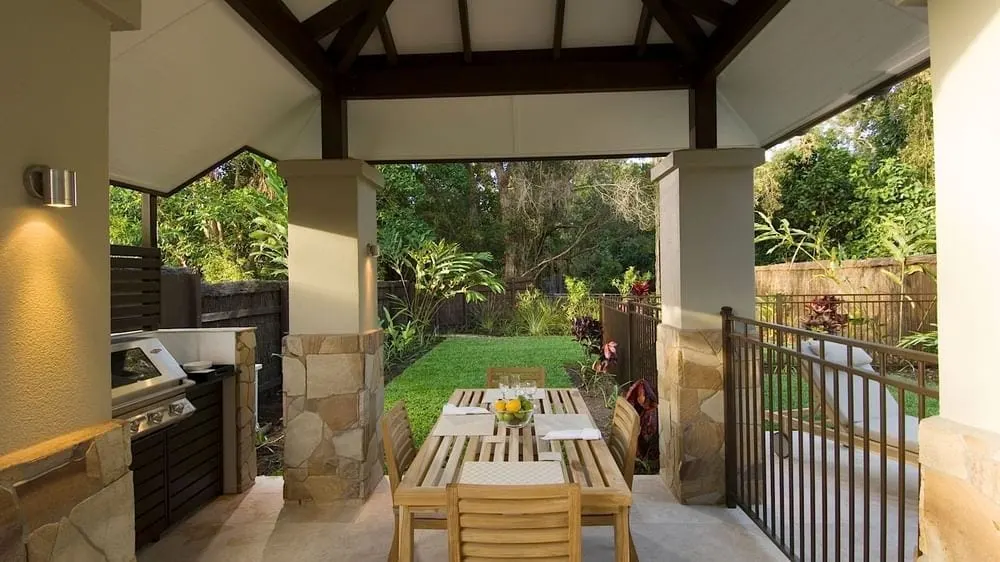 The covered outdoor kitchen and dining at a Pullman Sea Temple villa, a wall light beside the barbecue