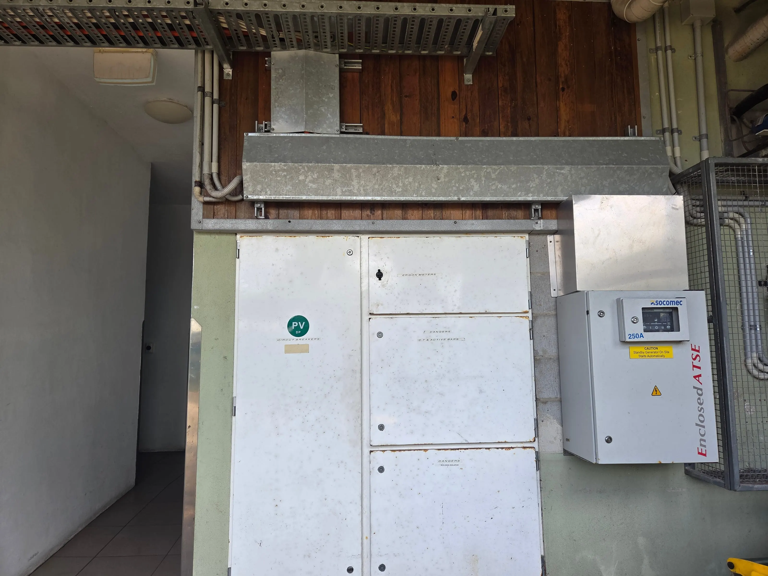 The main switchboard at Port Douglas Backpackers with its 250A automatic changeover beside it, a sticker on the changeover warning that the standby generator starts automatically